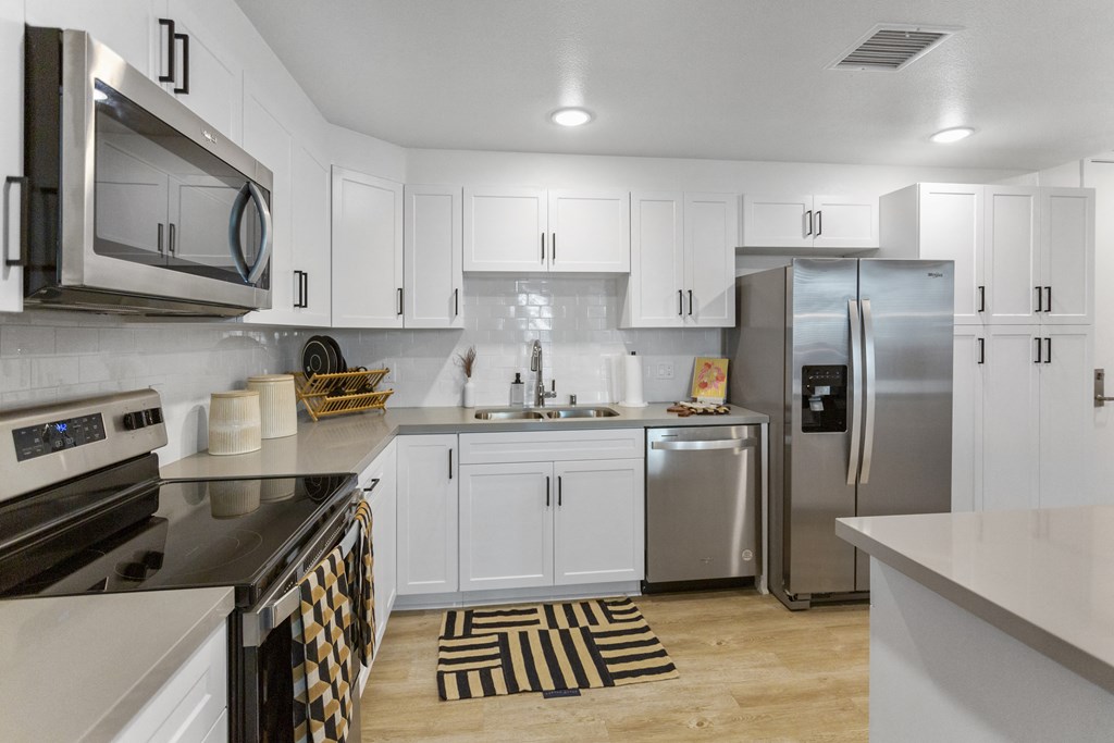 an open kitchen with white cabinets and stainless steel appliances at The Venue at Orange Apartments, Redlands, California