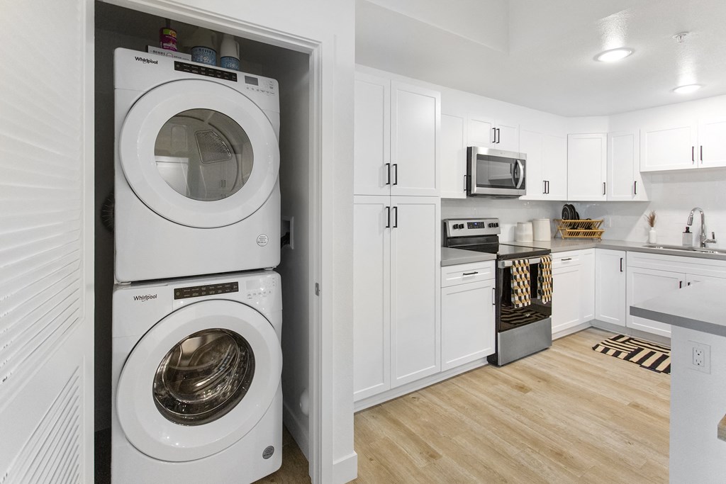 a white kitchen with a washing machine and a washer and dryer in it at The Venue at Orange Apartments, Redlands, 92373
