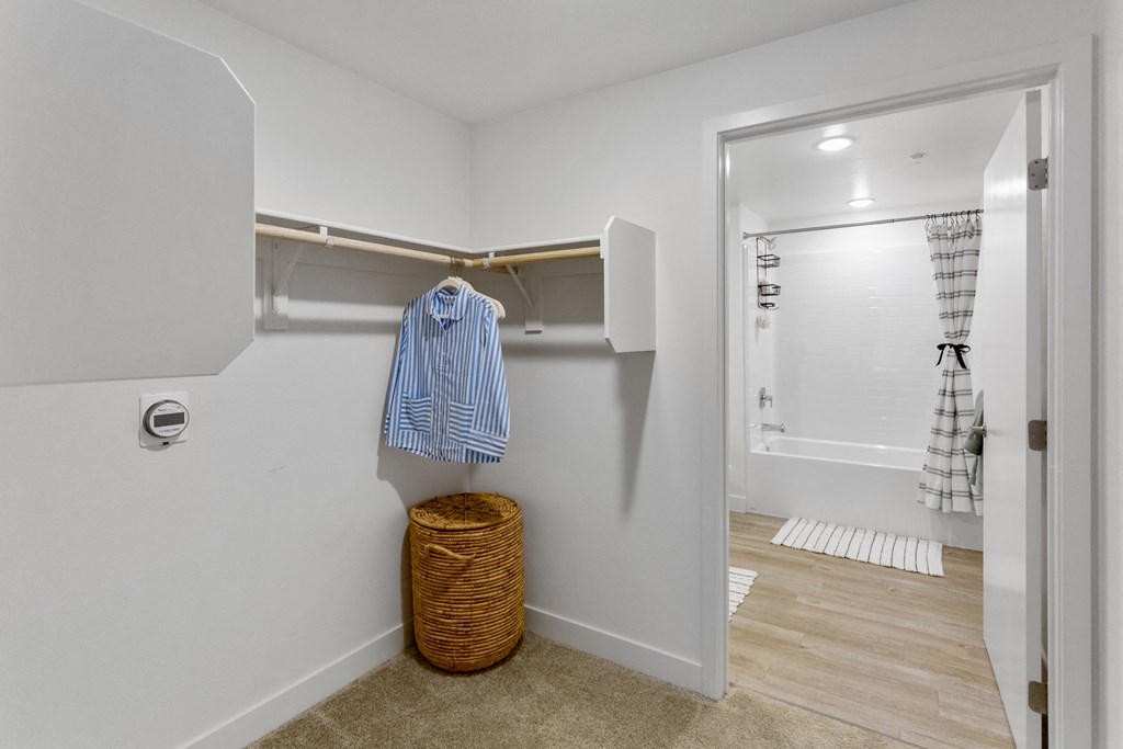 a bathroom with a closet and a shower and a basket on the floor at The Venue at Orange Apartments, Redlands