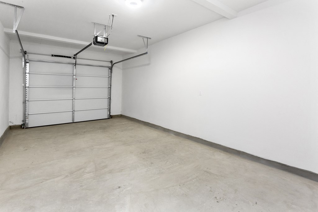 an empty room with a white wall and a garage door at The Venue at Orange Apartments, California, 92373