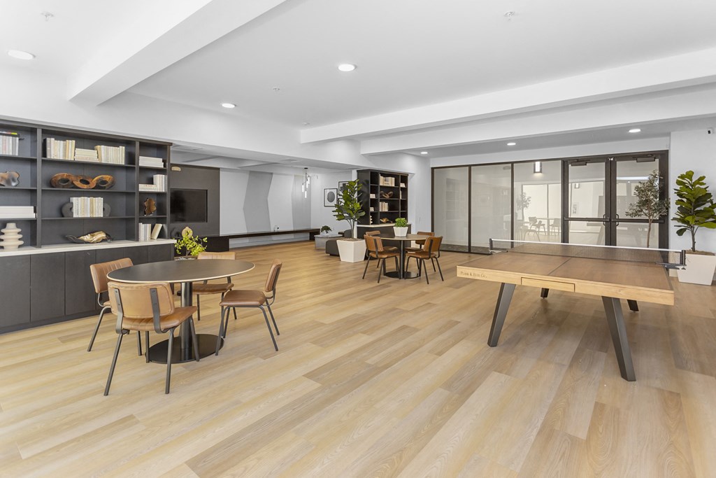 a living room with tables and chairs and a large window at The Venue at Orange Apartments, Redlands, CA