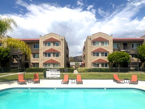 A swimming pool in front of a building with a sign that says "Pool Open 7am-10pm".