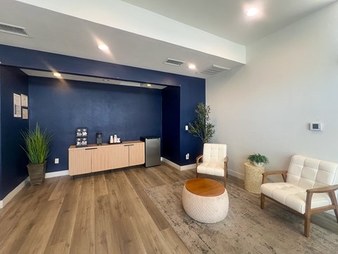 A room with a blue wall and wooden flooring has a white chair and a wooden table.