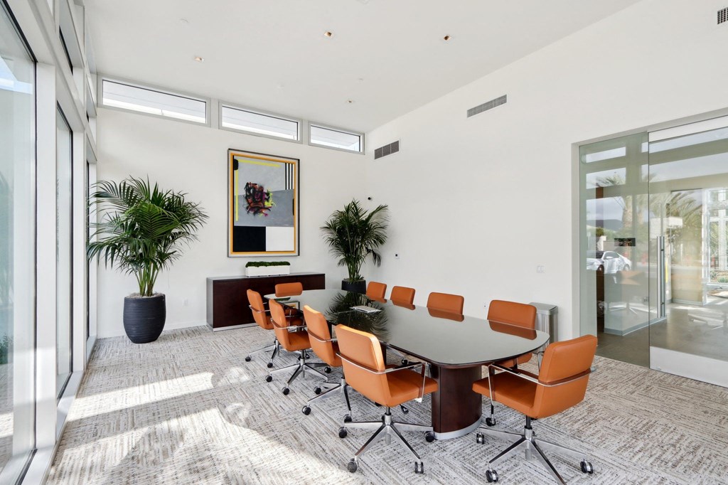 a conference room with a large table and orange chairs at The Max on Jefferson Apartments, California