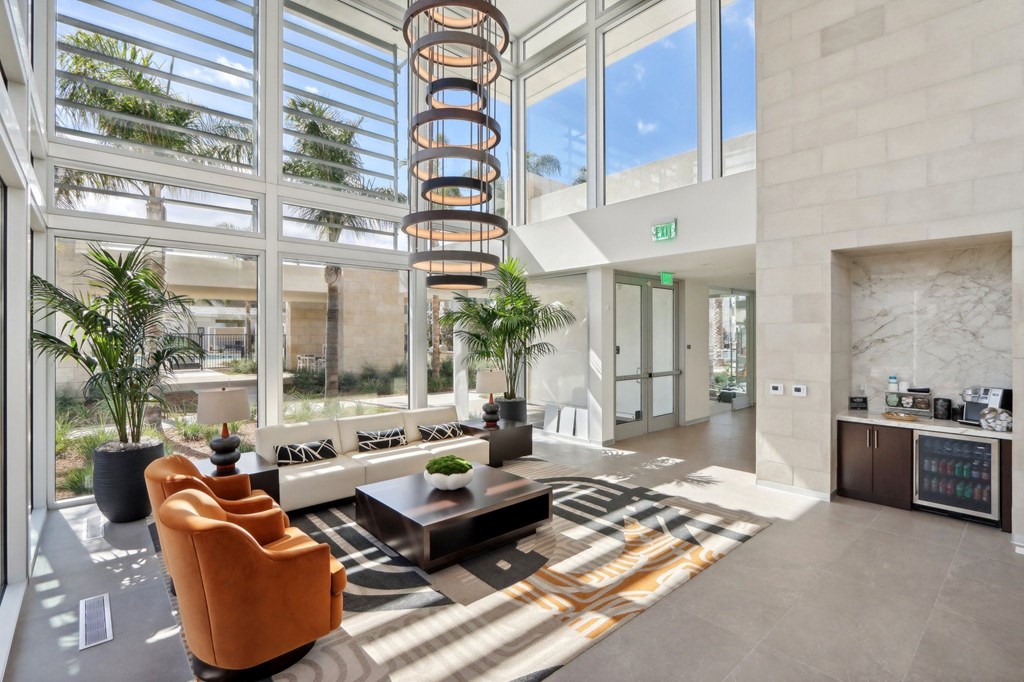 a lobby with a spiral staircase in the middle of a building with large windows at The Max on Jefferson Apartments, Murrieta, CA