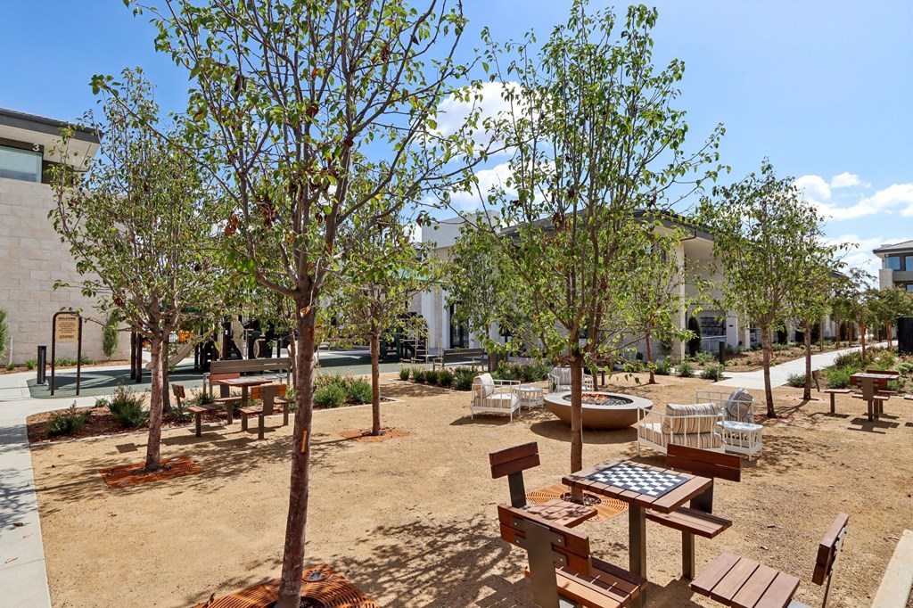 a courtyard with benches and trees and a building in the background at The Max on Jefferson Apartments, California, 92562