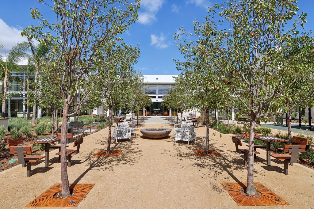 a courtyard with benches and trees and a building in the background at The Max on Jefferson Apartments, Murrieta, CA, 92562