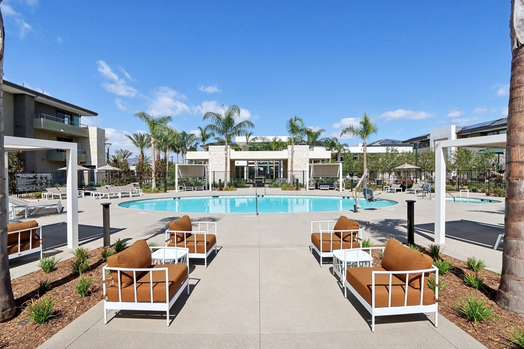 a swimming pool with lounge chairs and palm trees at the resort at The Max on Jefferson Apartments, Murrieta, CA