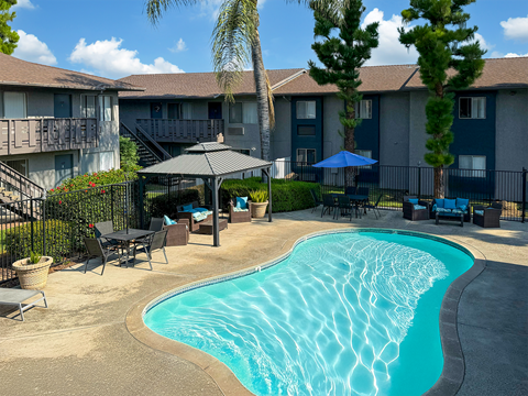 A swimming pool surrounded by a patio with chairs and umbrellas.
