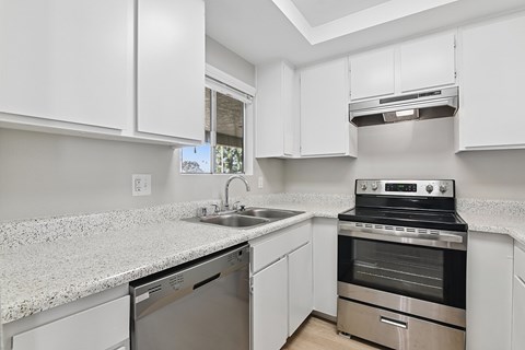 A kitchen with white cabinets and a granite countertop.