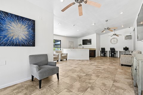 A living room with a grey armchair and a painting on the wall.