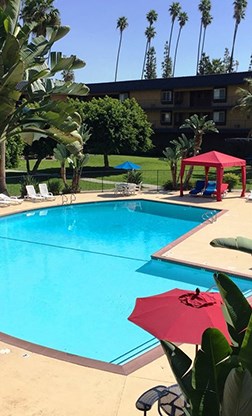 A red umbrella is next to a blue pool.