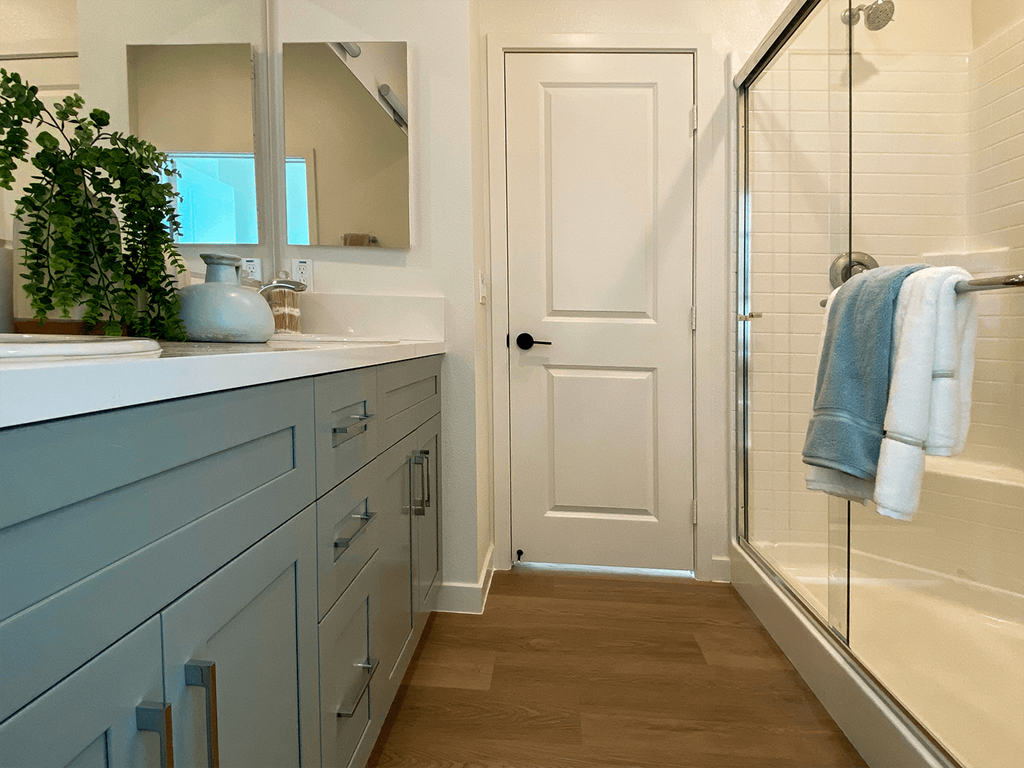 a bathroom with blue cabinets and a glass shower door