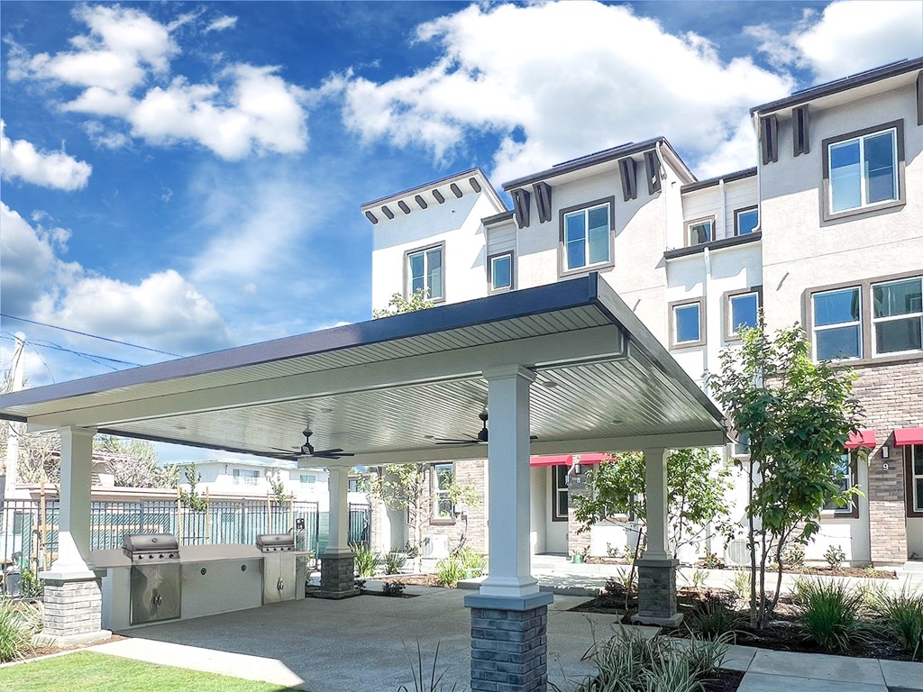 a patio with a roof in front of a building at The Willow Townhomes, Ontario, CA