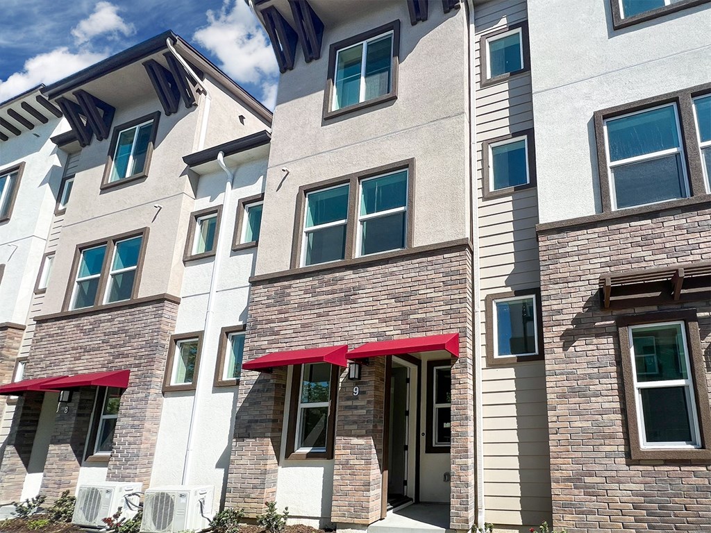 a brick apartment building with red umbrellas at The Willow Townhomes, California, 91762