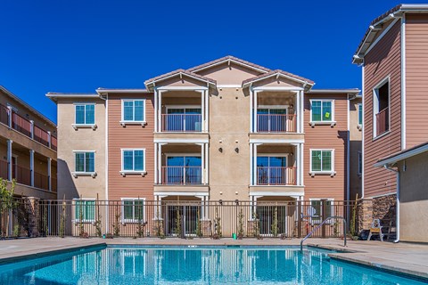 A large apartment building with a pool in front.