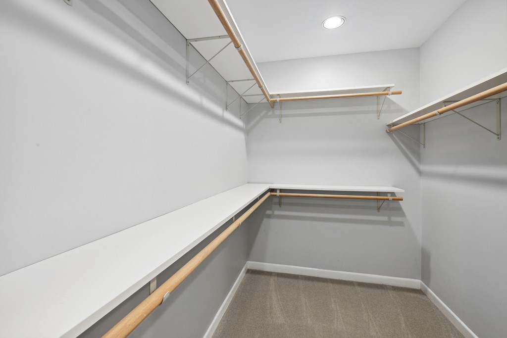 a walk in closet with white walls and wood shelves