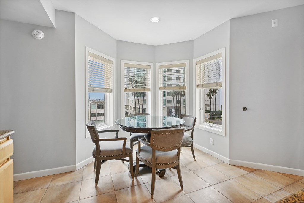 a dining area with a glass table and chairs and windows