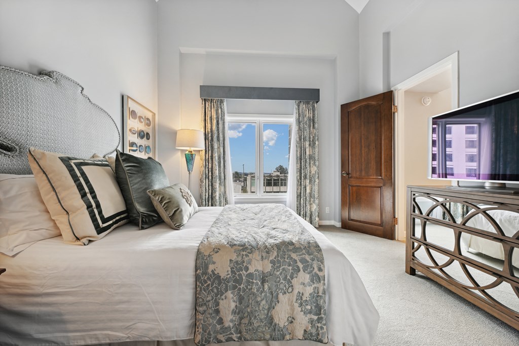 a bedroom with a bed and a tv and a window