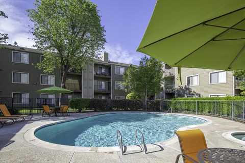 Resort-style swimming pool at Caifornia Place in gated pool area surrounded by lush greenery and blue skies for a beautiful and relaxing poolside experience