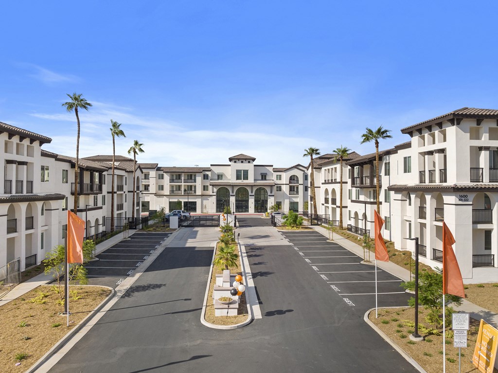 an empty street in front of apartments with palm trees at The Venue at Orange Apartments, California