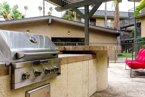 A silver outdoor grill is on a concrete counter.