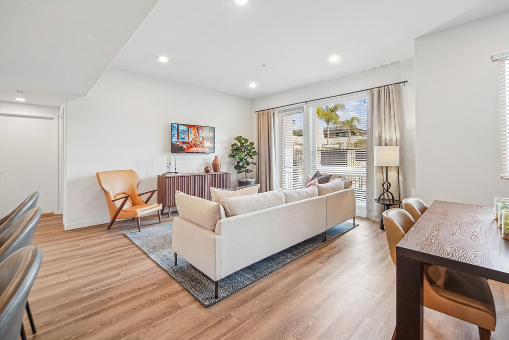 A living room with a white couch and a wooden table. at The Max on Jefferson Apartments, Murrieta, California