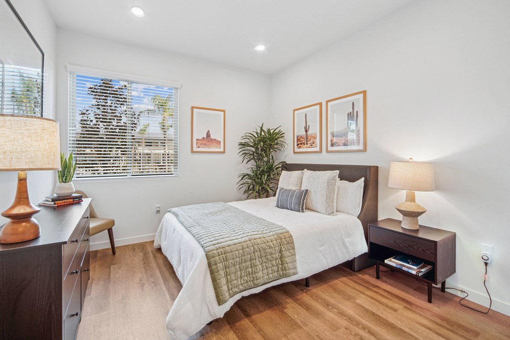 A bedroom with a bed, nightstand, and lamp at The Max on Jefferson Apartments, Murrieta, CA