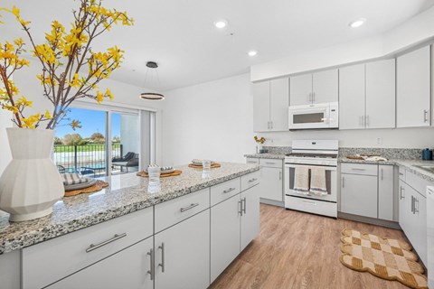 A kitchen with white cabinets and a granite countertop.