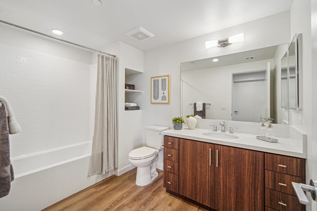A bathroom with a toilet, sink, and mirror. at The Max on Jefferson Apartments, California