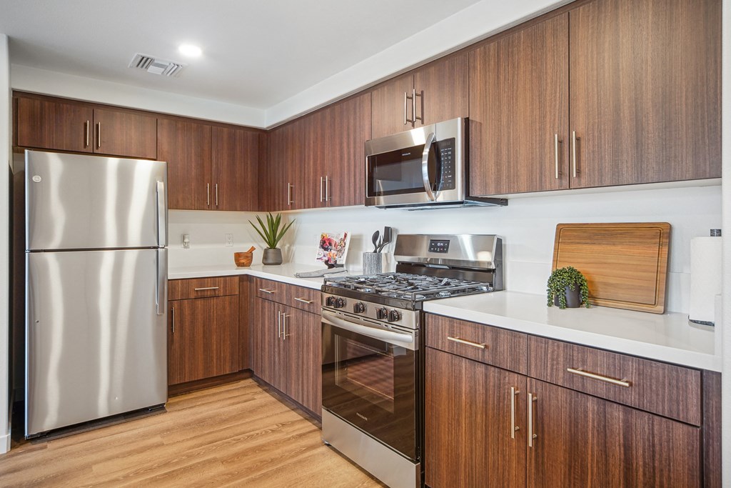 A modern kitchen with wooden cabinets and stainless steel appliances. at The Max on Jefferson Apartments, Murrieta, 92562
