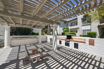 A patio with a wooden pergola and benches.