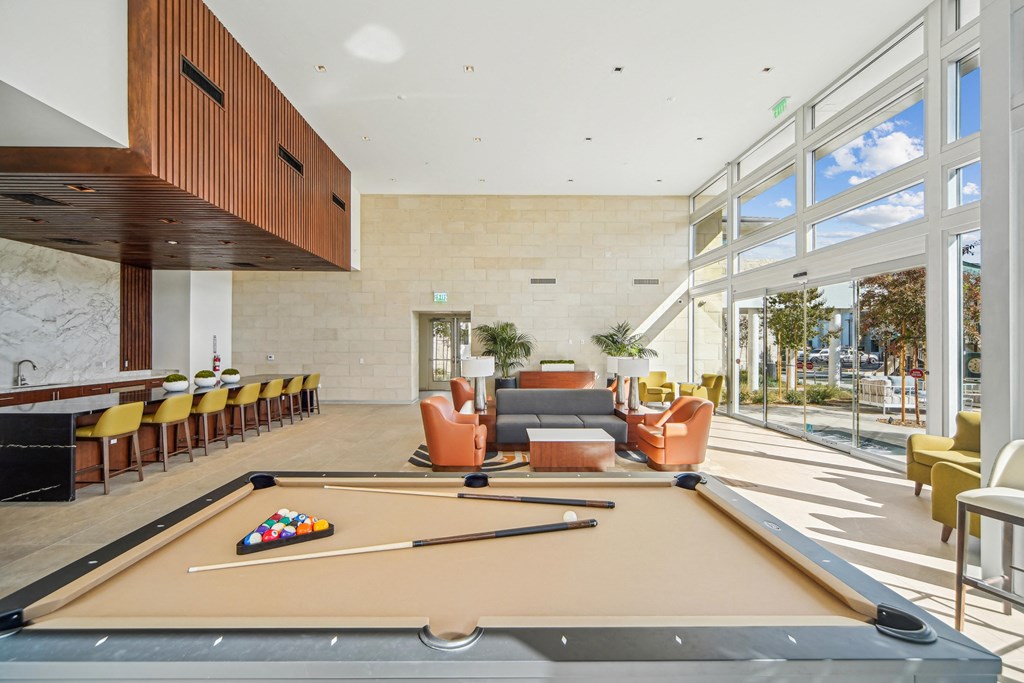 A pool table is in the middle of a room with a lot of chairs. at The Max on Jefferson Apartments, Murrieta, California