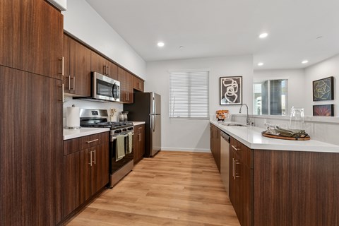 A modern kitchen with dark wood cabinets and stainless steel appliances.