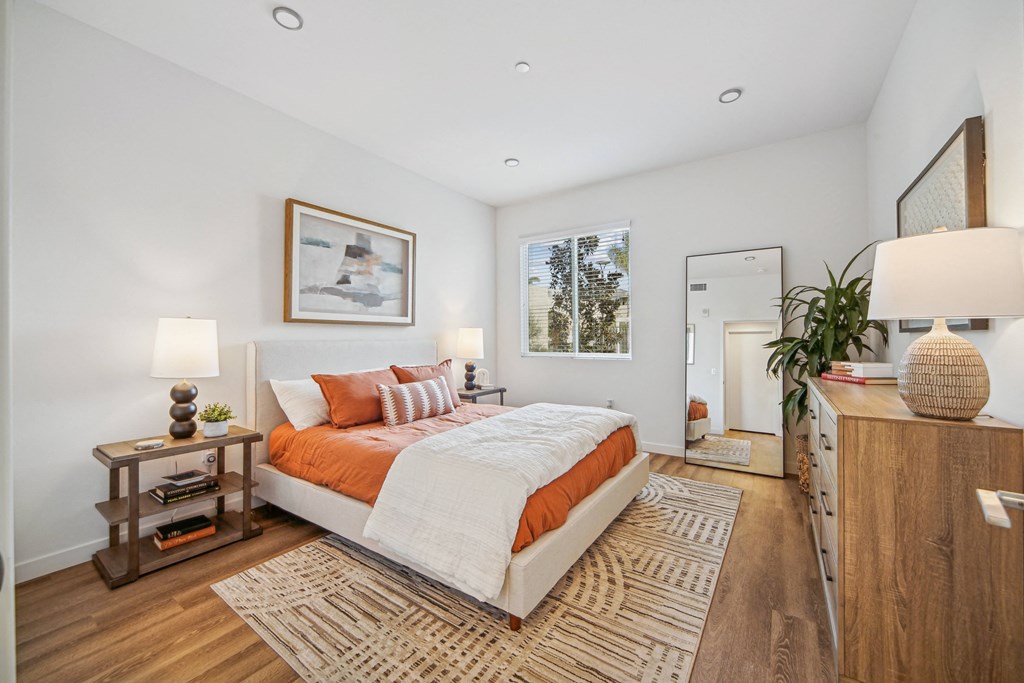A bedroom with a large bed and a wooden nightstand at The Max on Jefferson Apartments, Murrieta, California