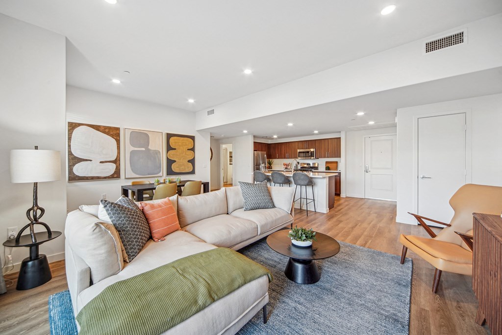 A living room with a white couch and a green throw pillow. at The Max on Jefferson Apartments, Murrieta, 92562