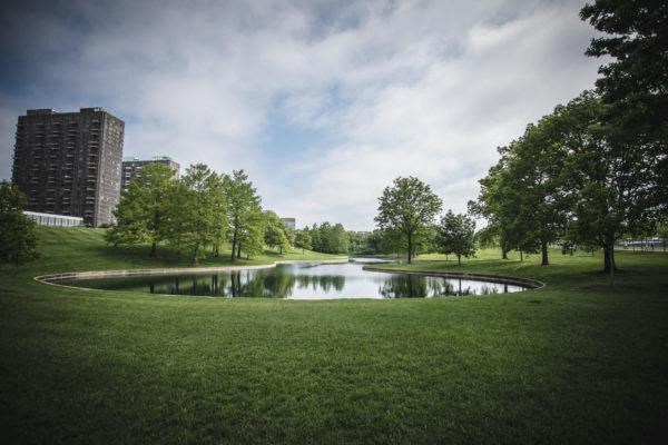 a small pond in the middle of the Gateway Arch Park with view of Mansion House Apartments in the background