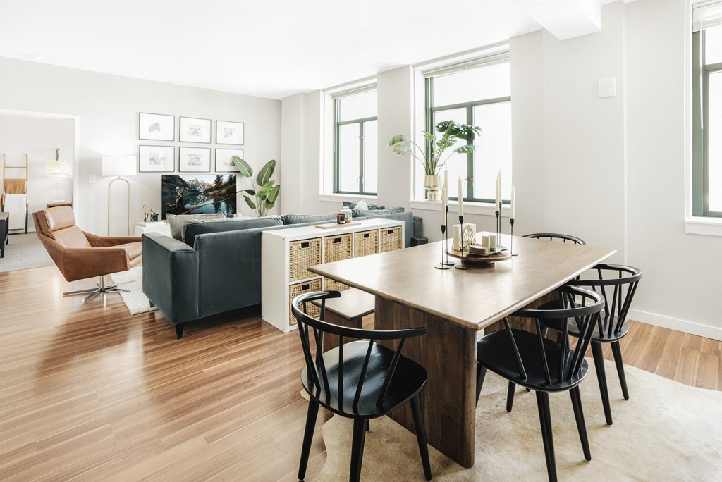 a view of a living room and dining room with a large wooden table and four black chairs
