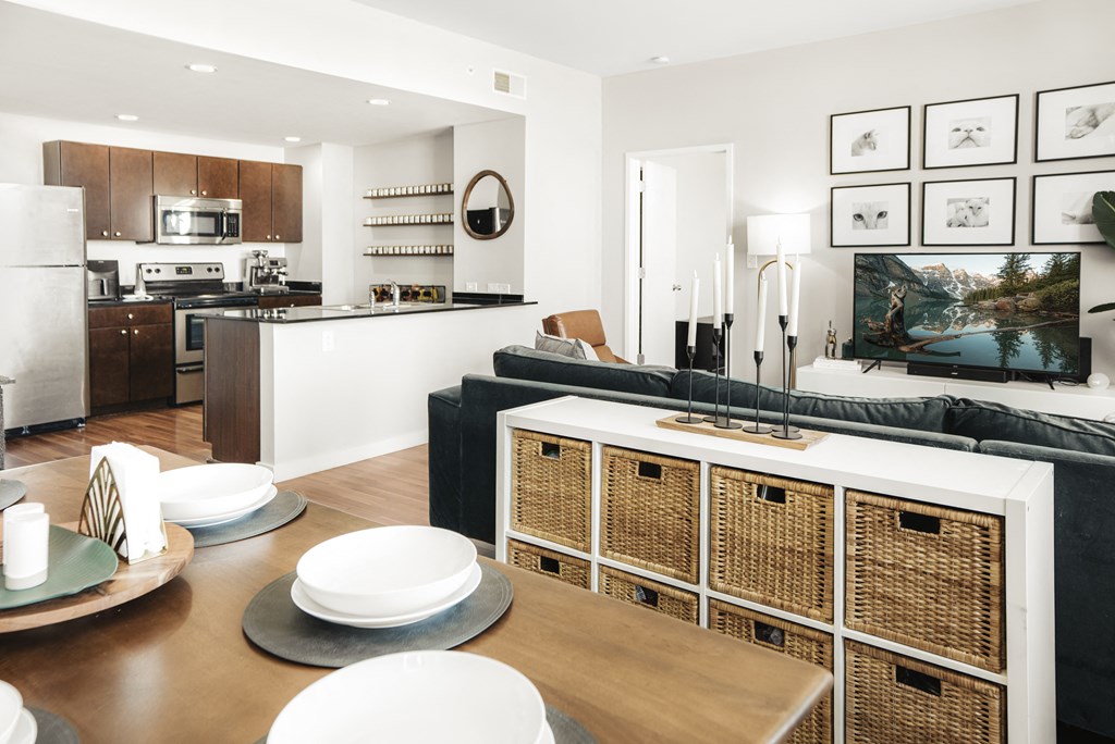 a living and dining area with a table and chairs and a kitchen in the background