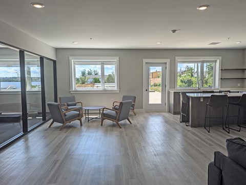 a common area with a table and chairs and a kitchen with a bar and windows