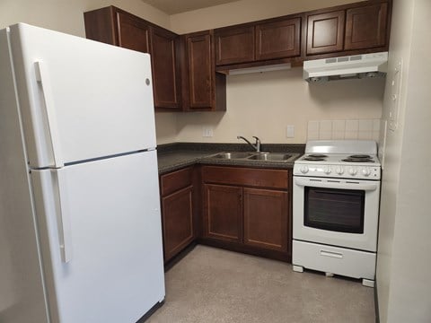 an empty kitchen with a refrigerator and a stove