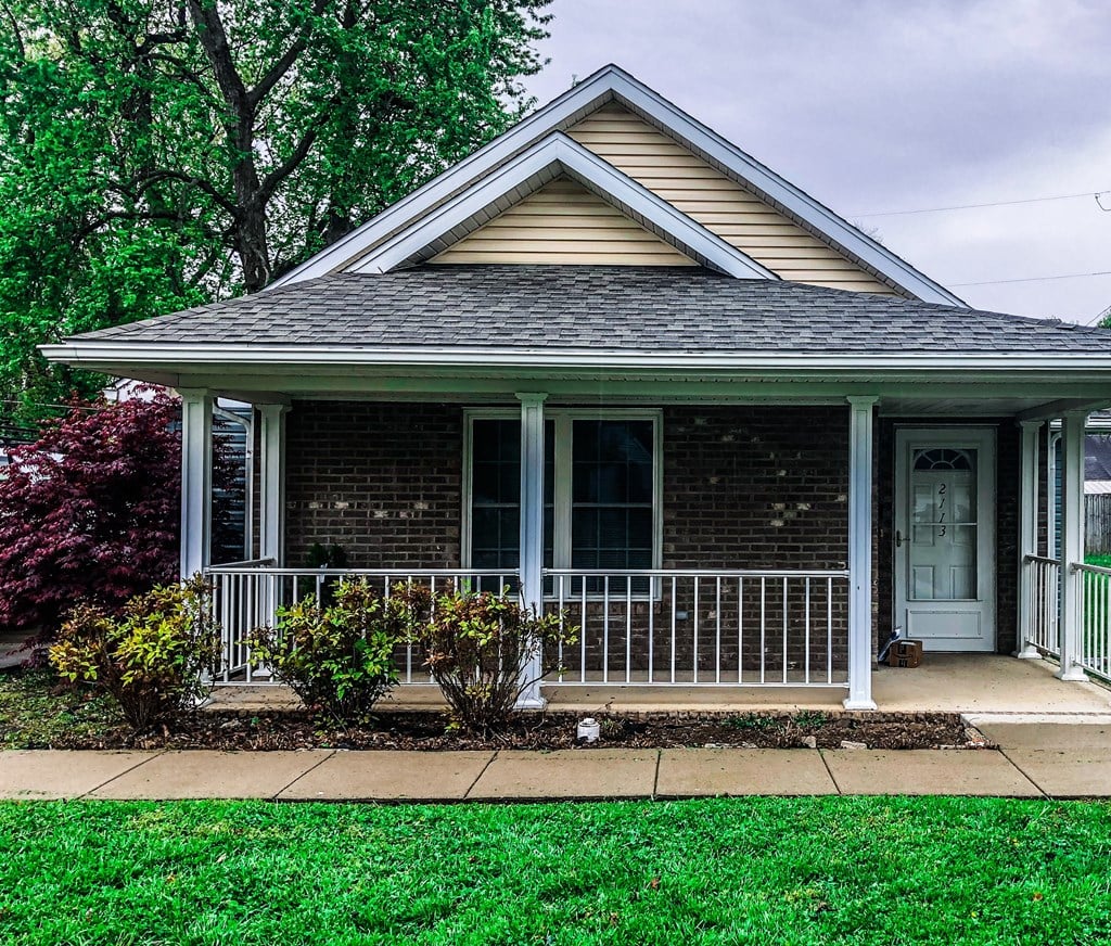 a small brick house with a porch and a door