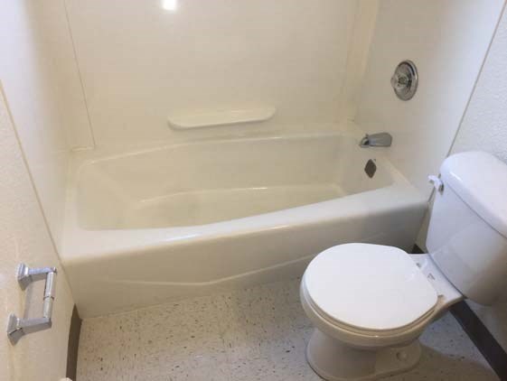 a white bathroom with a toilet and a bath tub