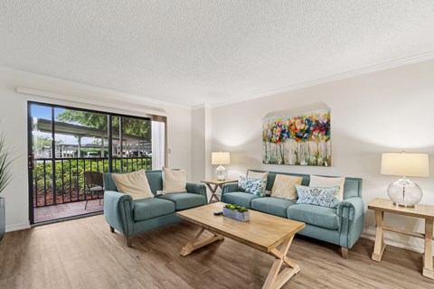 A living room with a blue couch and a wooden coffee table at Hampton Apartments, Florida