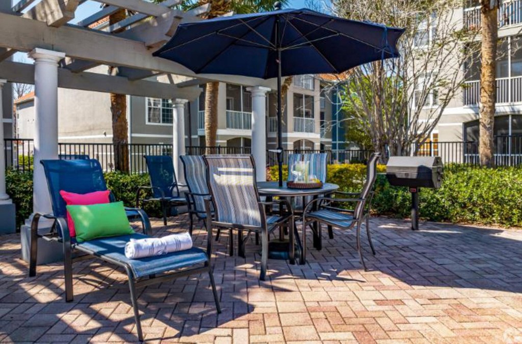 patio with a table and chairs under an umbrella at Mainstreet Apartments, Clearwater, FL
