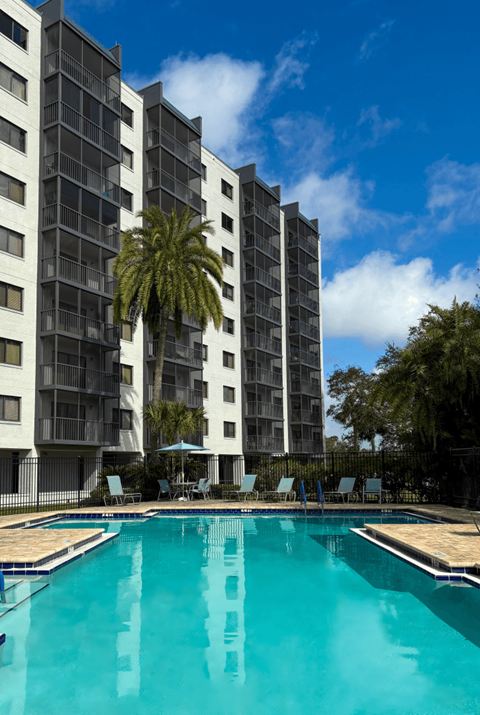 A tall building with a pool in front of it.