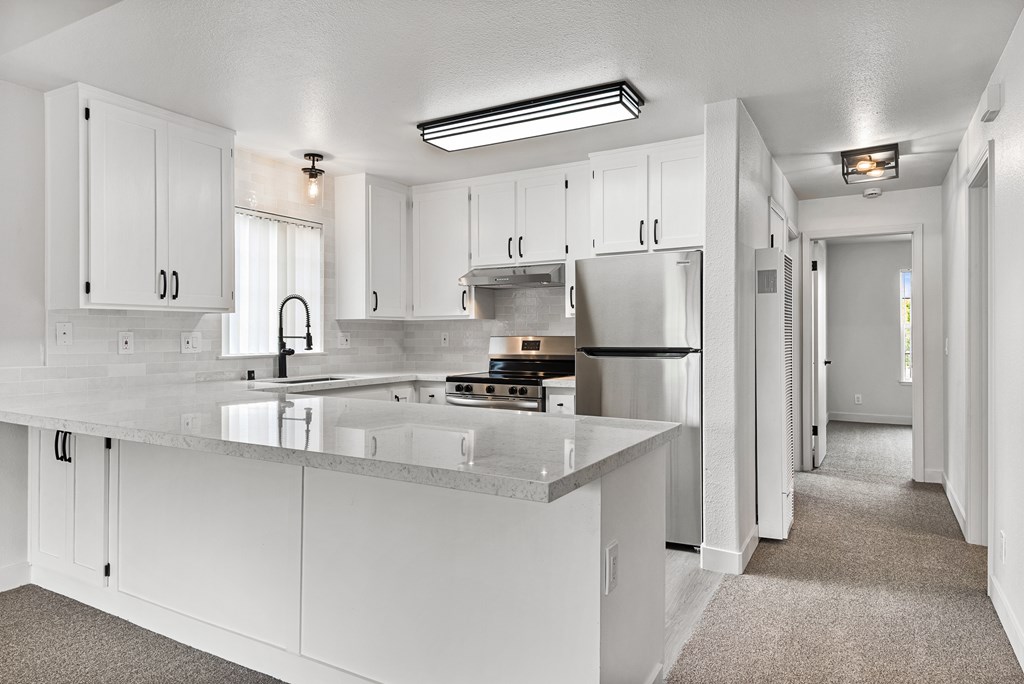 A kitchen with white cabinets and a quartz countertop.