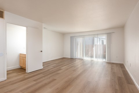 the living room of an apartment with wood flooring and a sliding glass door