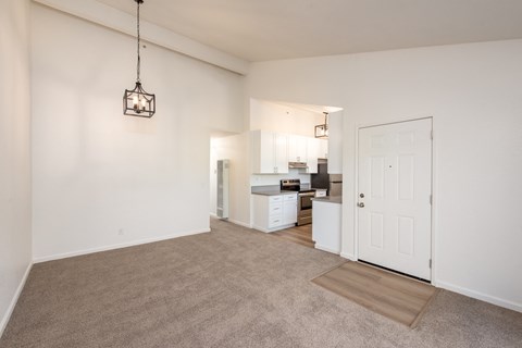 an empty living room and kitchen with white walls and carpet