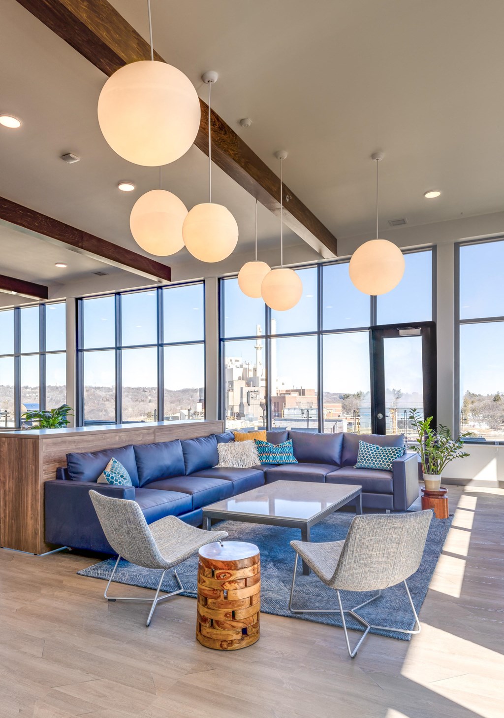a lounge area with blue couches and chairs and large windows